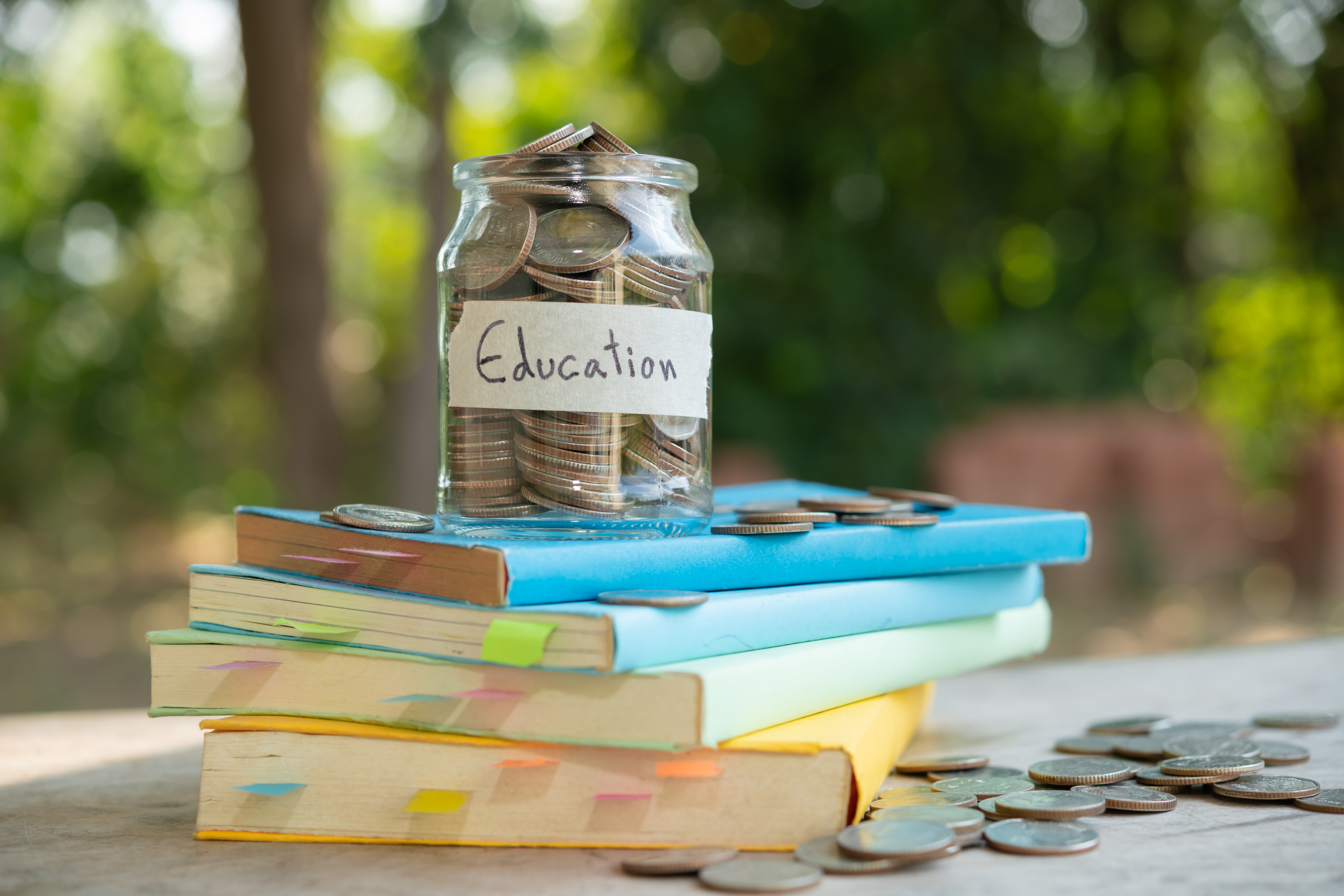 putting money coins saving in glass bottle for concept investment mutual fund finance and business, placed on the textbook. content money saving for education.